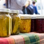 Jars of homemade corn relish and pickled cucumbers by Growing Sp